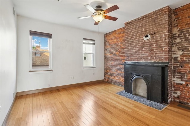 unfurnished living room with brick wall, baseboards, a ceiling fan, and light wood-style flooring
