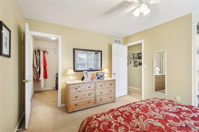 bedroom with light colored carpet, a walk in closet, baseboards, visible vents, and a closet