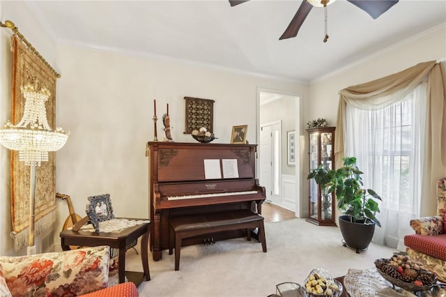 sitting room featuring carpet, ornamental molding, and ceiling fan with notable chandelier