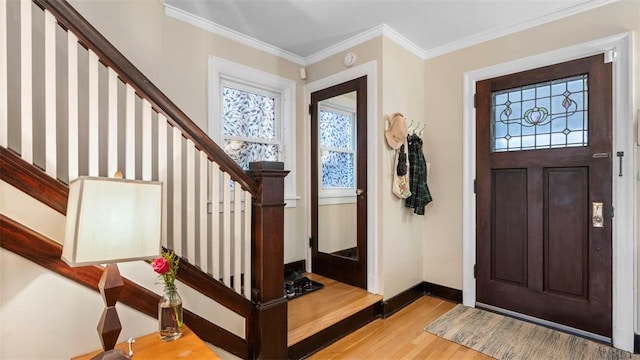 foyer entrance with stairs, crown molding, wood finished floors, and baseboards