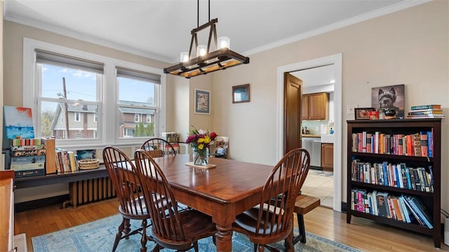 dining room featuring light wood-type flooring, a chandelier, and crown molding