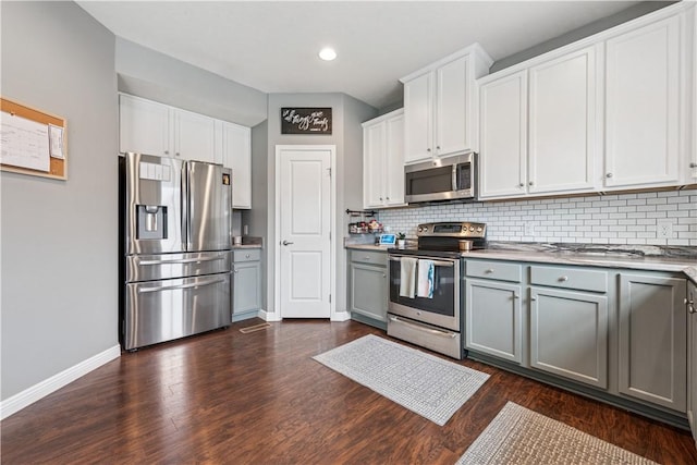 kitchen featuring stainless steel appliances, baseboards, gray cabinetry, and tasteful backsplash