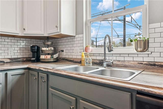 kitchen with tasteful backsplash, a wealth of natural light, gray cabinets, and a sink