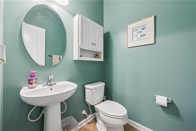 half bath featuring baseboards, tile patterned flooring, and toilet