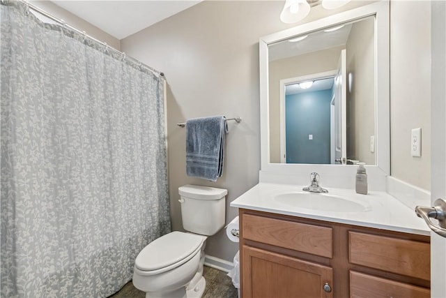 bathroom featuring baseboards, vanity, and toilet