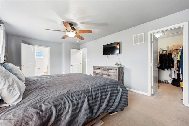 bedroom featuring visible vents, light carpet, a walk in closet, baseboards, and ensuite bathroom