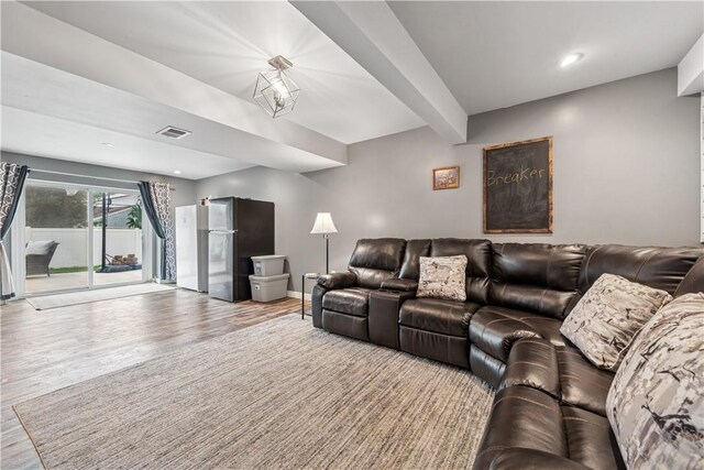 living room with wood finished floors, visible vents, and baseboards