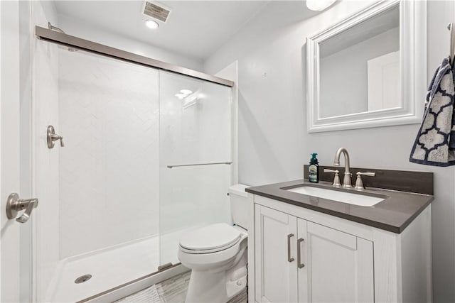 bathroom featuring toilet, vanity, visible vents, and a stall shower