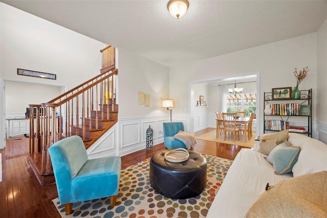 living room with hardwood / wood-style floors, stairs, a chandelier, and wainscoting