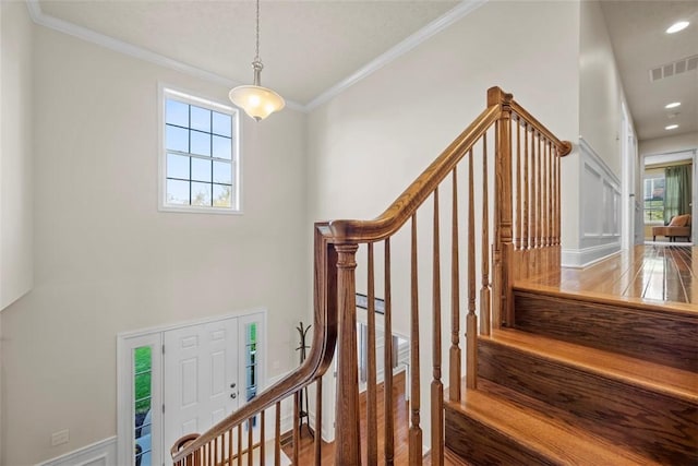 stairs featuring crown molding and wood finished floors