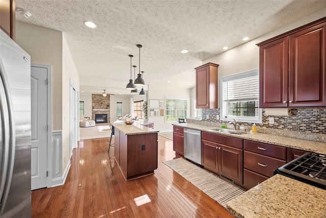 kitchen with stainless steel appliances, open floor plan, a textured ceiling, dark wood finished floors, and backsplash