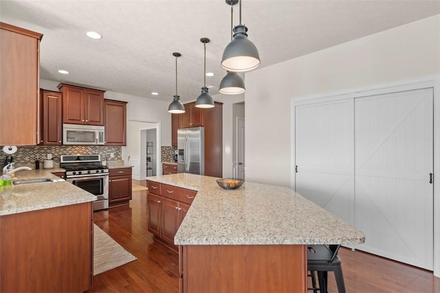 kitchen with stainless steel appliances, a sink, decorative backsplash, dark wood-style flooring, and recessed lighting