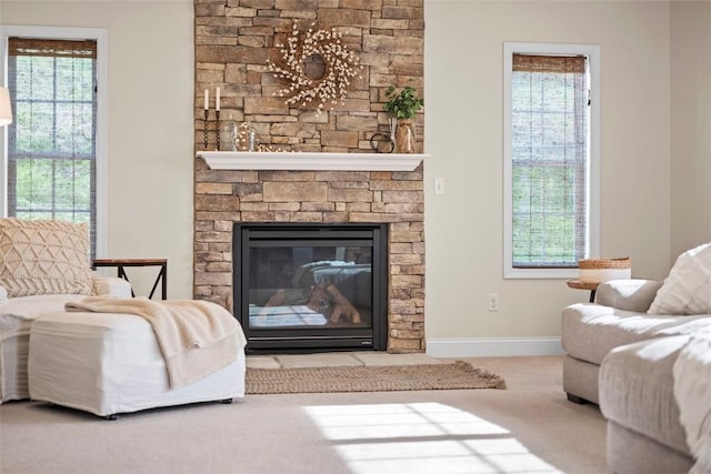 living room with carpet, baseboards, a stone fireplace, and plenty of natural light