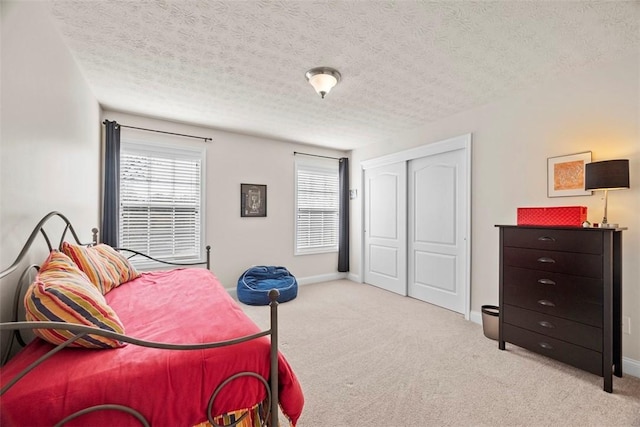 carpeted bedroom featuring a closet, a textured ceiling, and baseboards