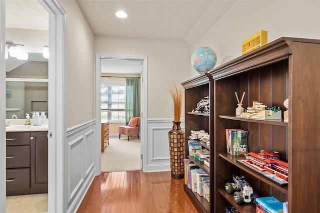 corridor featuring wainscoting, light wood finished floors, and recessed lighting