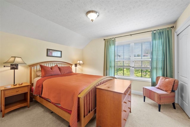 bedroom featuring light carpet, lofted ceiling, a textured ceiling, and a closet