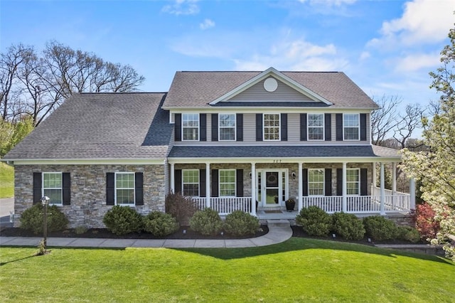colonial inspired home featuring stone siding, a front lawn, roof with shingles, and a porch