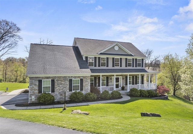 colonial-style house with stone siding, a porch, a front lawn, and a shingled roof