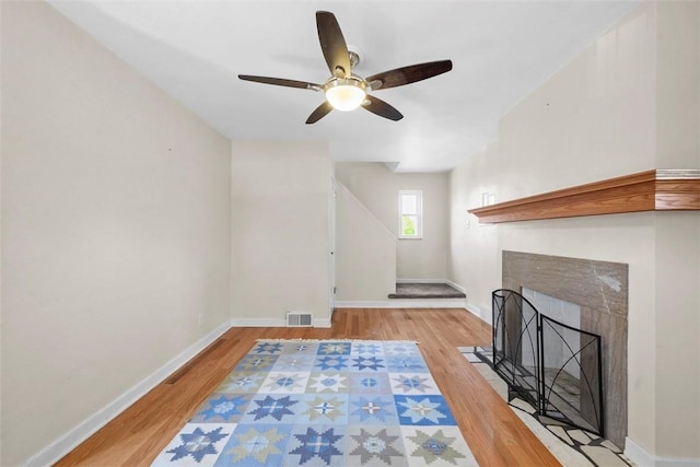 unfurnished living room featuring wood finished floors, visible vents, baseboards, and ceiling fan