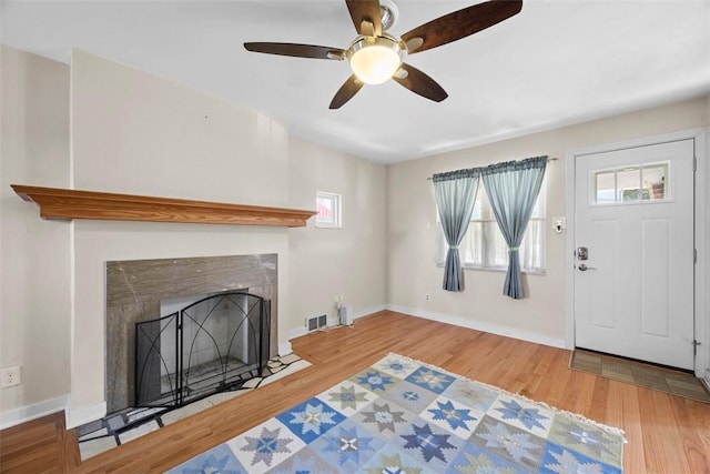 living area featuring a ceiling fan, wood finished floors, and a healthy amount of sunlight