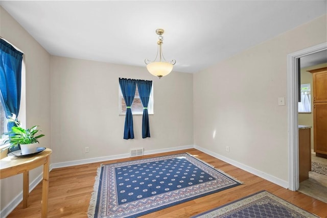 empty room featuring baseboards, light wood finished floors, visible vents, and plenty of natural light