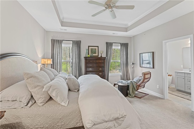 bedroom featuring ensuite bathroom, baseboards, visible vents, light colored carpet, and a raised ceiling