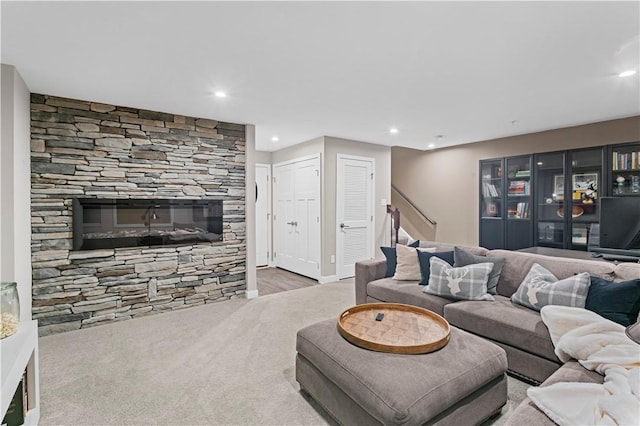 living area featuring wood finished floors, a stone fireplace, recessed lighting, and stairs