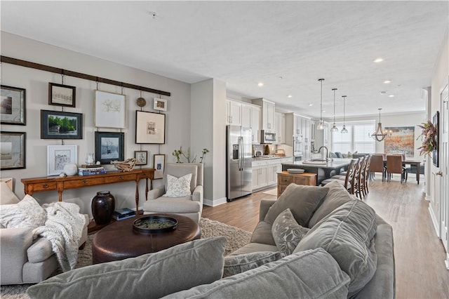 living area featuring baseboards, an inviting chandelier, light wood-style floors, and recessed lighting