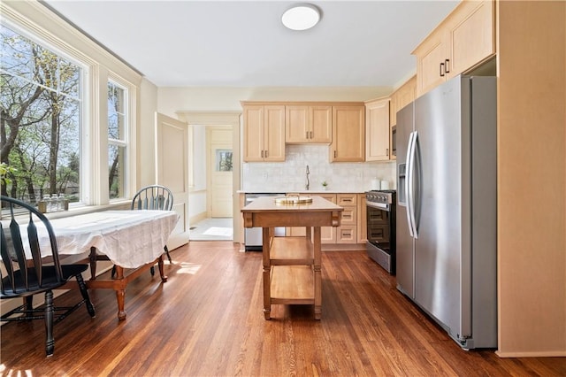 kitchen with light brown cabinets, dark wood-style flooring, stainless steel appliances, and light countertops