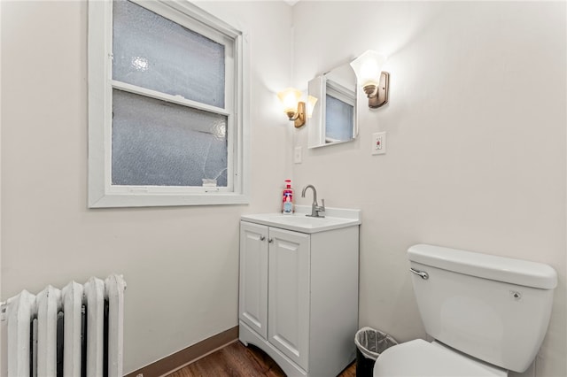 129 S Braddock Ave, Point Breeze, PA 15221 - half bath featuring vanity, wood finished floors, toilet, baseboards, and radiator heating unit