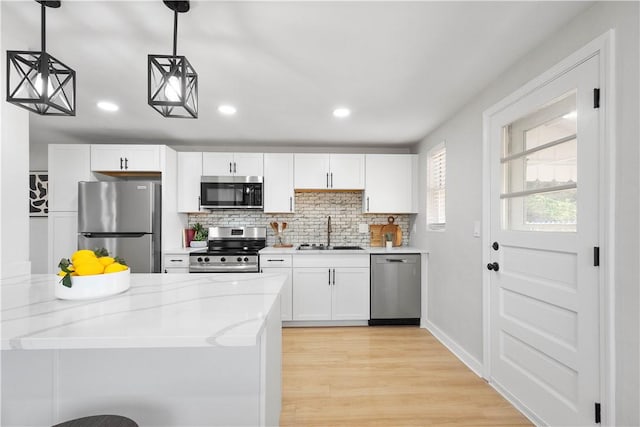 239 Merritt Ave, Carrick, PA 15227 - kitchen featuring stainless steel appliances, a sink, backsplash, white cabinetry, and hanging light fixtures