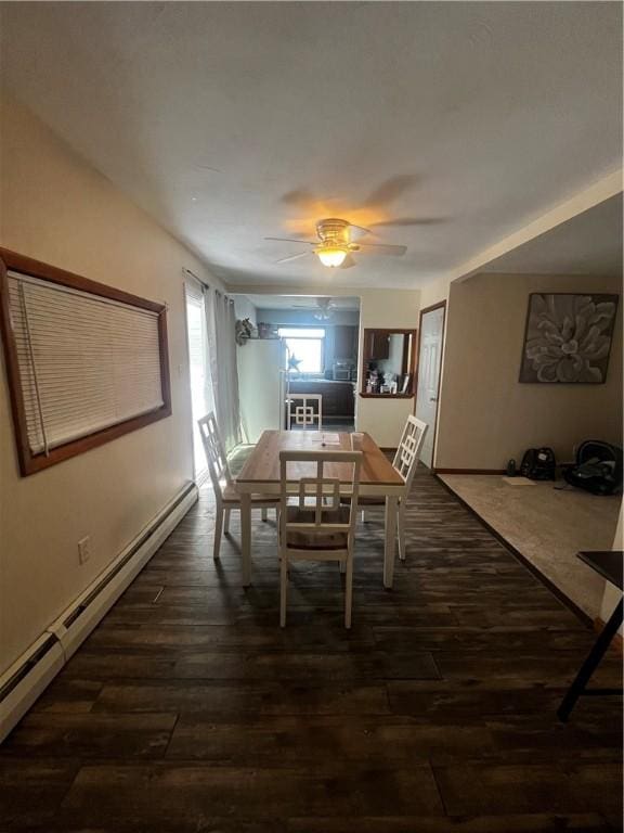 dining area featuring dark wood finished floors, a ceiling fan, and baseboard heating