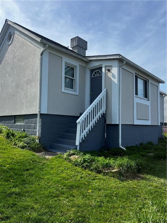 exterior space with stairs, a lawn, and a chimney