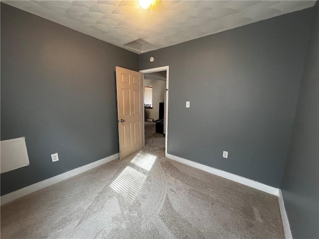 spare room featuring baseboards and light carpet