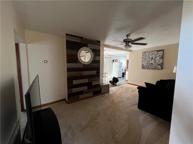 carpeted living area featuring baseboards and ceiling fan