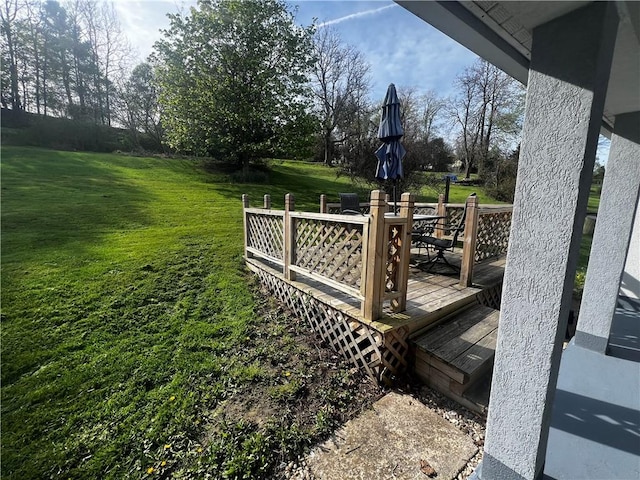 wooden deck featuring outdoor dining space and a lawn