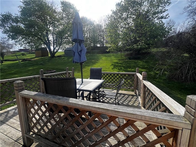 wooden terrace with outdoor dining area and a lawn