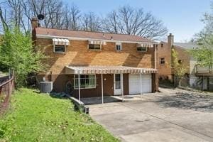 back of house featuring fence, a chimney, a garage, and concrete driveway