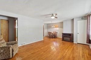 living area featuring wood finished floors, baseboards, and ceiling fan