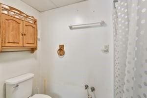 full bathroom with a drop ceiling, a shower with shower curtain, and toilet