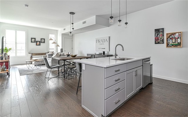 kitchen featuring gray cabinetry, stainless steel dishwasher, dark wood-style flooring, and a sink