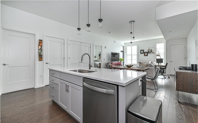 kitchen featuring stainless steel dishwasher, a sink, dark wood-style flooring, open floor plan, and light countertops