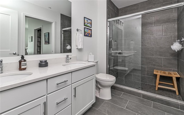 bathroom featuring a shower stall, toilet, a sink, and double vanity