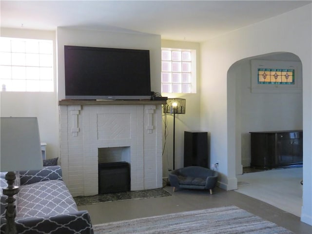 living room featuring a brick fireplace and concrete floors
