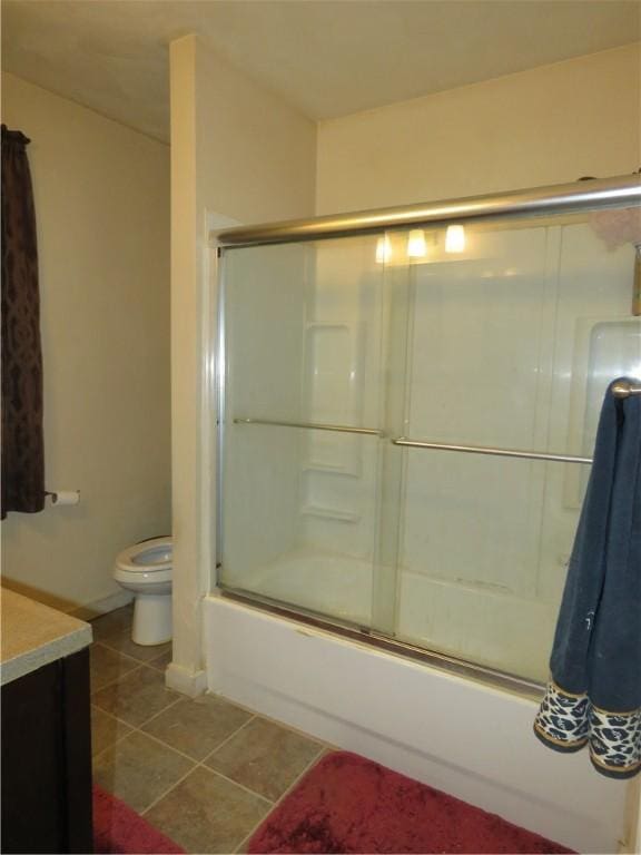full bath with shower / bath combination with glass door, tile patterned flooring, toilet, and vanity
