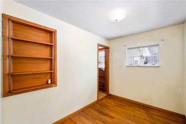 empty room featuring wood finished floors and baseboards