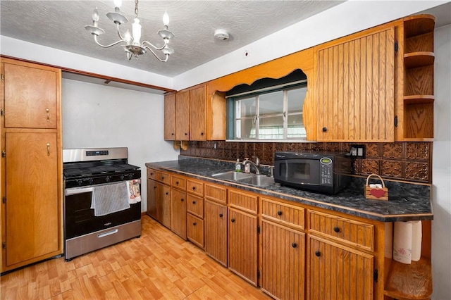 kitchen featuring light wood-style flooring, a sink, tasteful backsplash, black microwave, and stainless steel gas stove