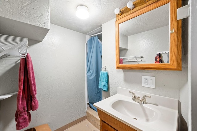 full bathroom featuring curtained shower, baseboards, a textured ceiling, and vanity