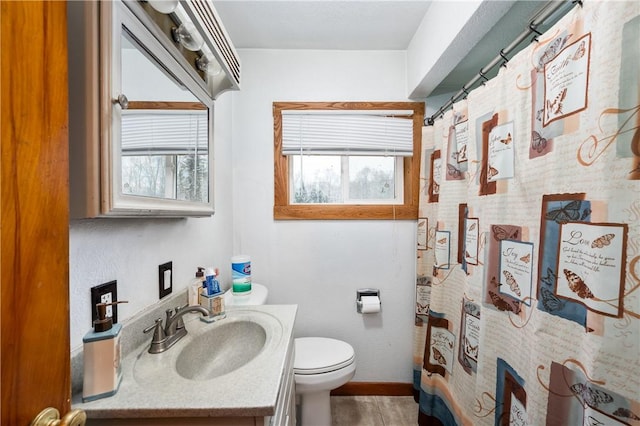 bathroom with toilet, vanity, a shower with shower curtain, and baseboards