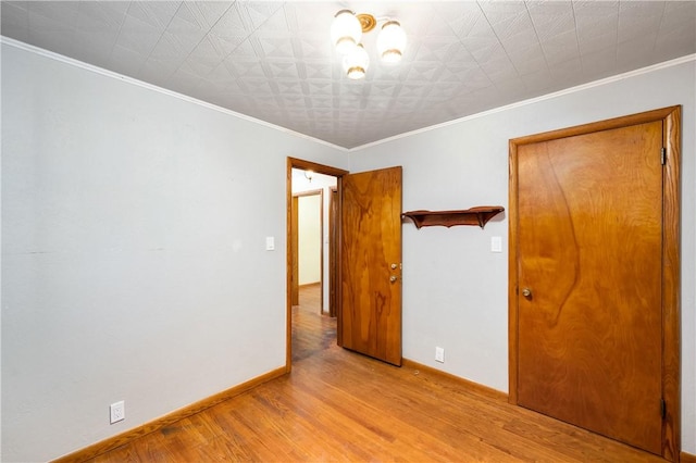 empty room with baseboards, ornamental molding, and wood finished floors
